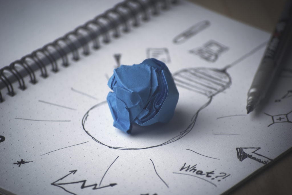 A sketch of a lightbulb with a crumpled blue piece of paper in the middle of the drawing