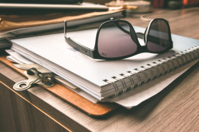 Sunglasses sitting on top of a book on a desk