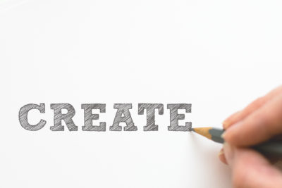 A person writing the word "create" in pencil