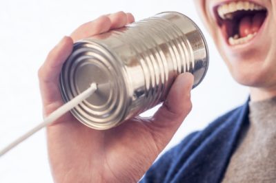 A person yelling into a tin can with a string attached to it