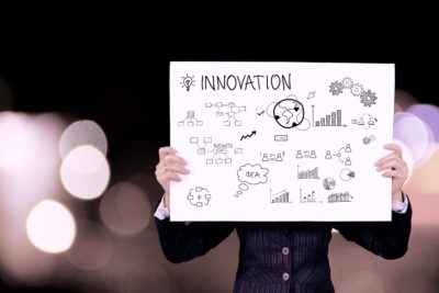 A person holding a whiteboard with the words "Innovation" and drawings written on it