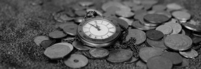 A pocket watch laying on top of coins