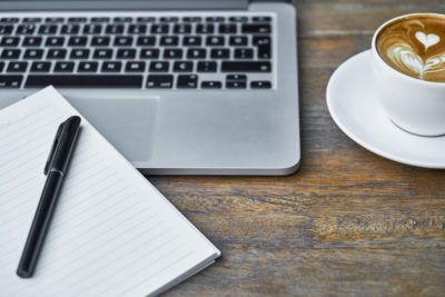 laptop, notepad, pen, and coffee cup