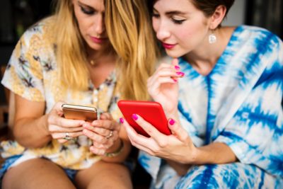 2 women holding and looking at their cellphones