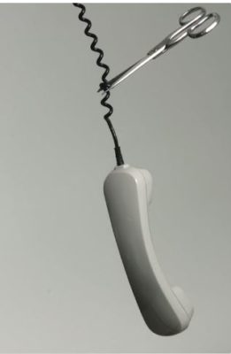A phone dangling from the cord and a hand holding a pair of scissors cutting the cord.