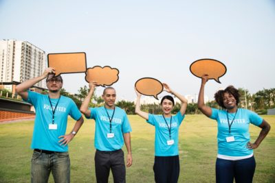 4 volunteers holding cut-out text bubble signs