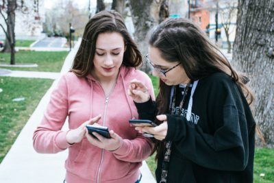 2 women holding and looking at their cellphones