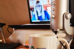 patricia shown on computer screen, showing her desk, mic, mug and set up for an online workshop