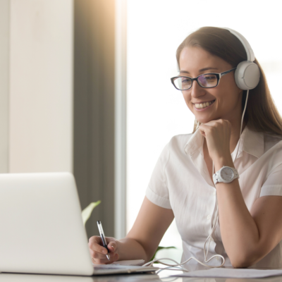 person looking on laptop, headset on, smiling