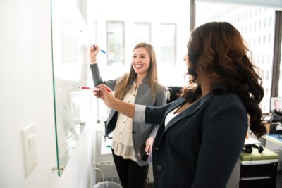two women working on a white board training