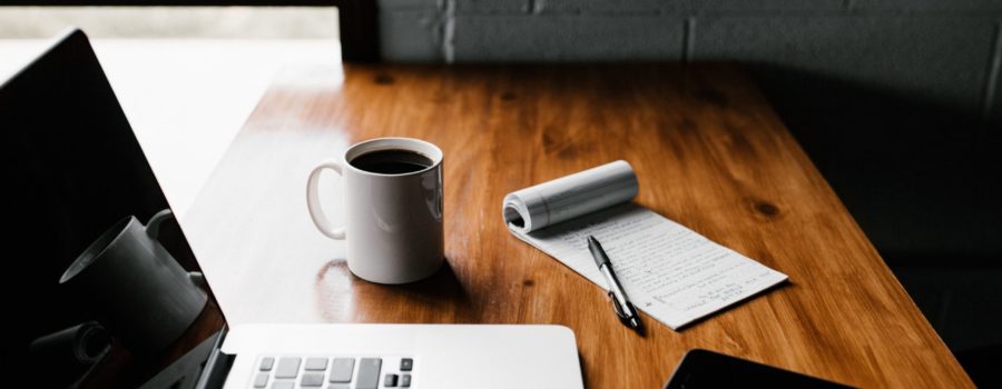 Leading video meetings on zoom: laptop, notepad, pen, and coffee cup