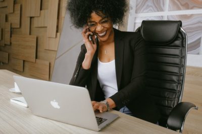 Woman sitting at laptop, talking on cellphone