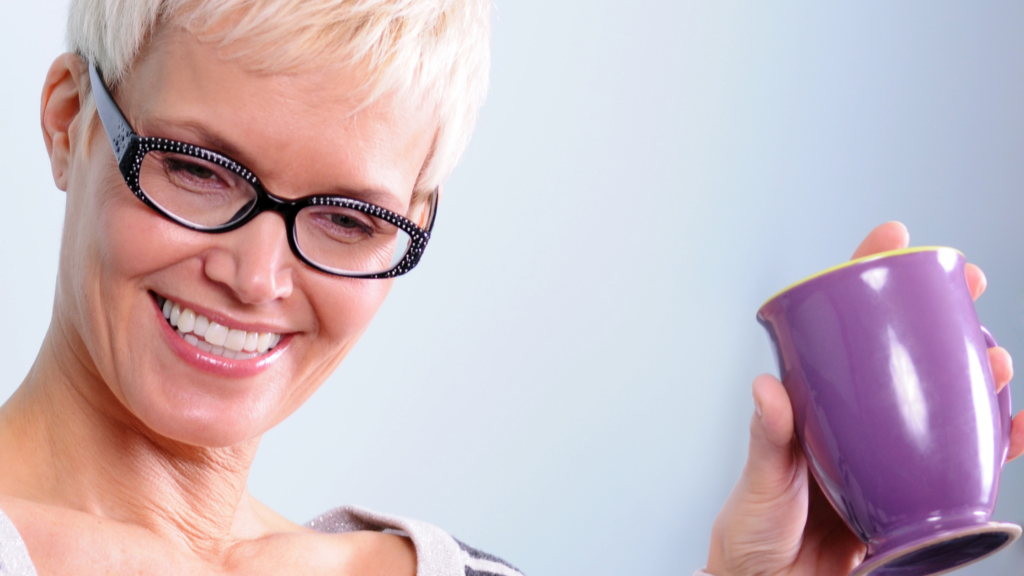 woman holding up a cup of tea smiling