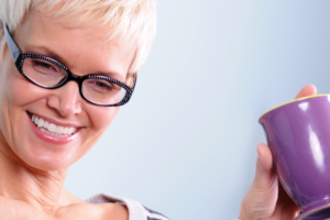 woman holding up a cup of tea smiling