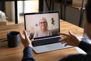 woman smiling on computer, as a person watching laptop training session online