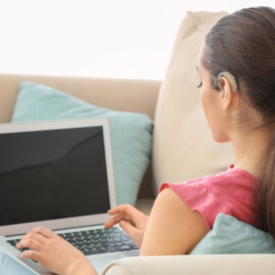 woman with hearing aid closed captions and laptop