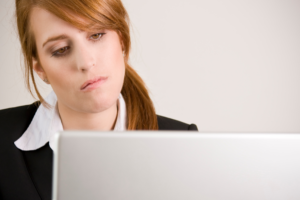 woman looking tired and staring at her computer screen