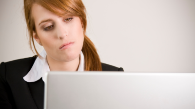 woman looking tired and staring at her computer screen