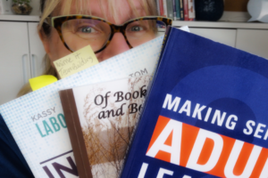 picture of woman holding several books on her summer reading list