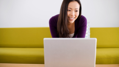 woman smiling at computer, creating in Canva.