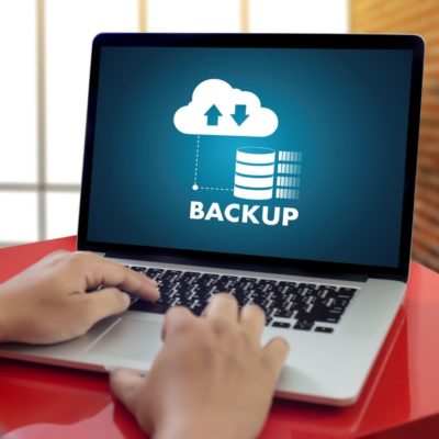 image of hands on a laptop with picture of BACKUP up and download on the screen
