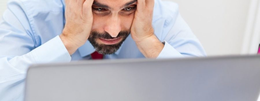 Computer crashed, man holding hands on face looking at computer