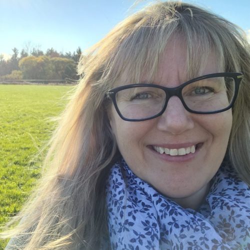 image of Patricia Regier smiling with a green field in the background