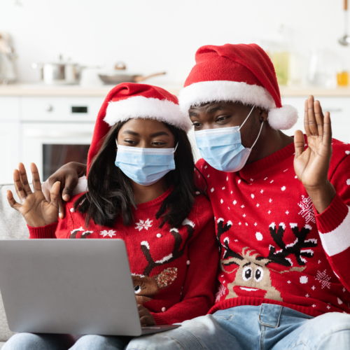 image of 2 people in festive clothes and masks waving to people on their laptop for a hybrid holiday party