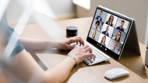 person typing on keyboard on computer screen multiple video tiles of people