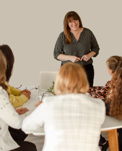 Patricia speaking to a group. She is a white woman with brown hair wearing a black and white striped top and black pants