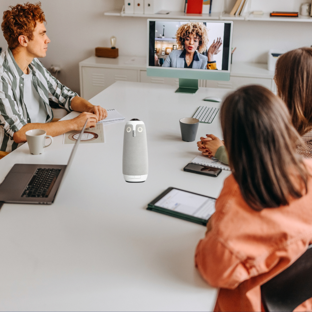 People in a meeting onsite and hybrid blended audience online. The Meeting Owl is on the table.