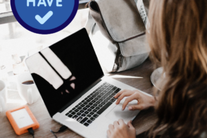 Person typing on a laptop while travelling, with backup drive.