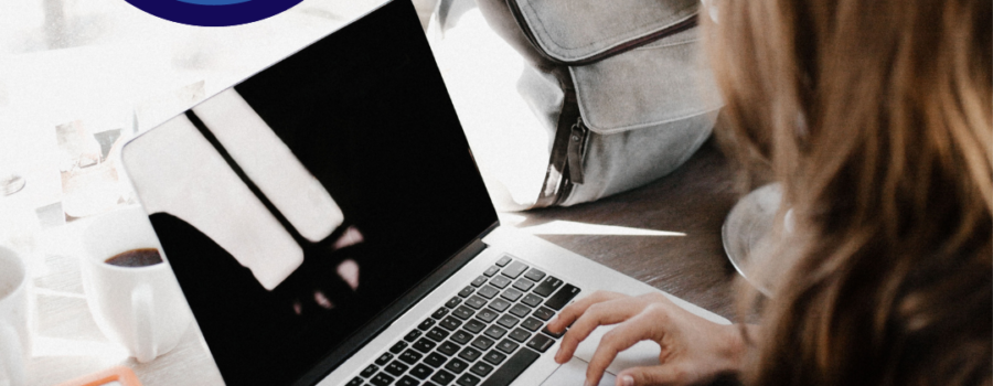 Person typing on a laptop while travelling, with backup drive.